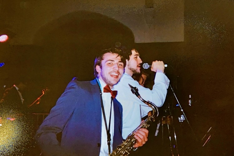 polaroid of function band gig. Blue suit, leaning back with a tenor saxophone