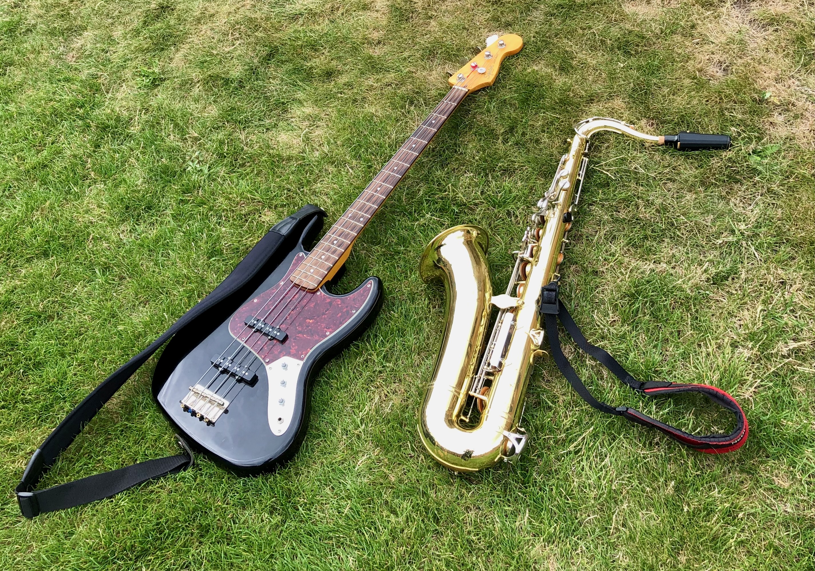 Jonathan Parapadakis's tenor saxophone and Louis Henry's bass guitar on grass at a wedding